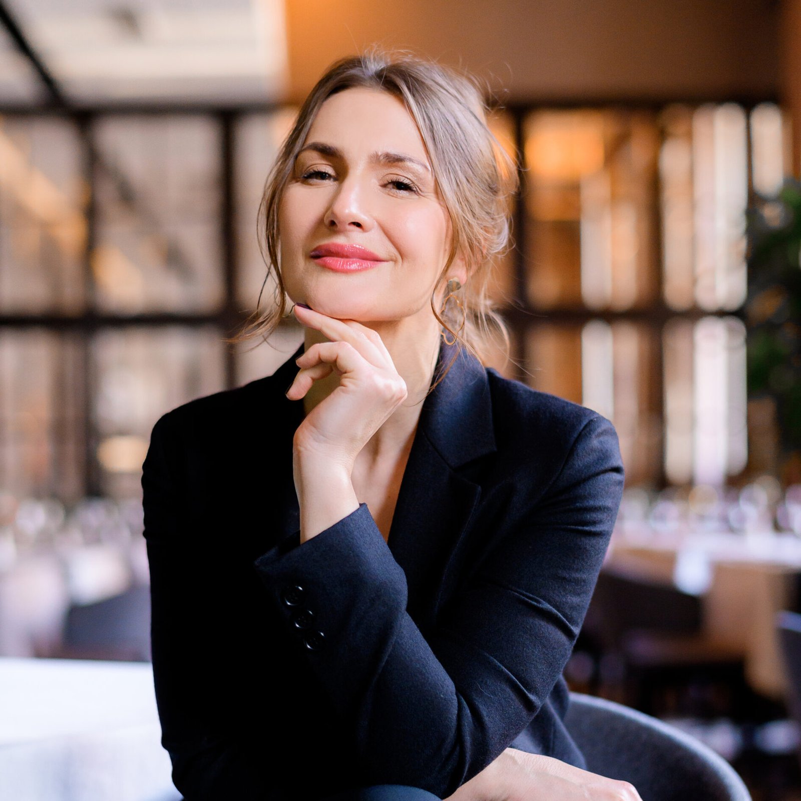 Portrait of smiling successful businesswoman looking into camera sitting in the restaurant. Business lady with stylish hairstyle wears elegant suit. Business meeting. Attractive appearance